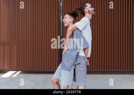 Coppia che si alza da dietro davanti al muro Foto Stock