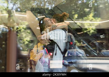 Coppia felice abbracciandosi visto attraverso la finestra di vetro Foto Stock