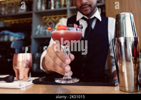 Barman con bicchiere e cocktail al bar Foto Stock