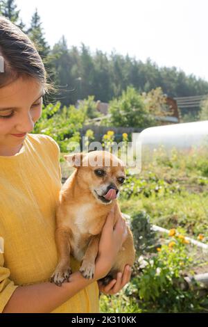 Ragazza sorridente che porta il cane in giardino Foto Stock