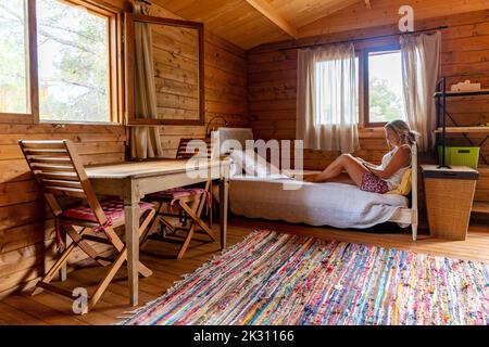 Donna matura seduta sul letto a casa Foto Stock