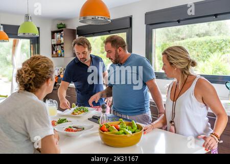 Amici che preparano il cibo insieme in cucina a casa Foto Stock