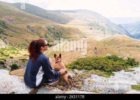 Donna con cane seduto di fronte alla montagna Foto Stock