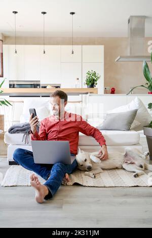 Sorridente freelance che parla in videochiamata tramite telefono cellulare a casa Foto Stock