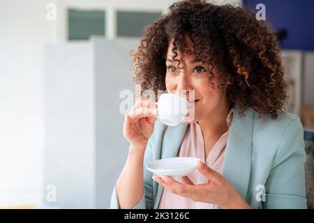 Donna d'affari matura che beve caffè nel tempo di pausa sul posto di lavoro Foto Stock