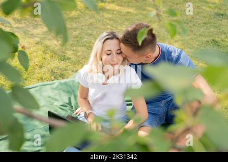 Affettuoso giovane baciante ragazza godendo pic-nic al parco Foto Stock