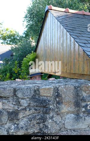 Uomo che sbirciava da dietro il muro di pietra Foto Stock