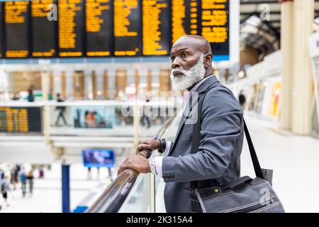 Uomo d'affari senior e premuroso con borsa per laptop alla stazione ferroviaria Foto Stock