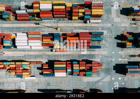 Drone aereo vista dall'alto verso il basso di container sparsi in un porto trafficato, concetto logistico e commerciale internazionale Foto Stock