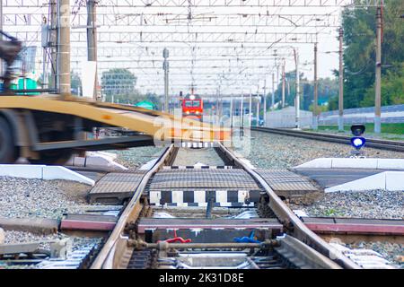 Il carro attrezzi ha superato un incrocio ferroviario di fronte a un treno in avvicinamento, con messa a fuoco selettiva Foto Stock