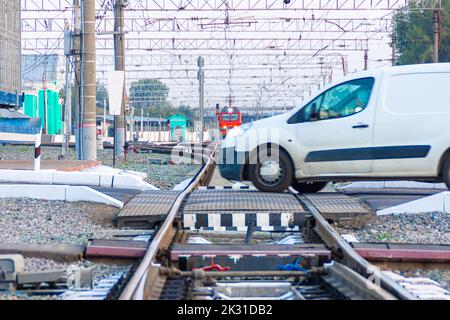 Kemerovo, Russia - 01 settembre 2022. Un'autovettura commerciale per consegne puntuali attraversa la ferrovia che attraversa la parte anteriore del treno, selettiva fo Foto Stock