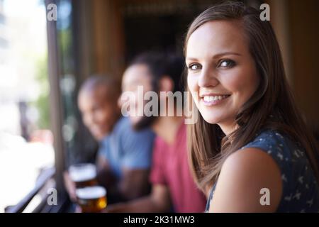 Sorseggiando un drink al bar. Un piccolo scatto di giovani amici che beve un drink in un bar. Foto Stock