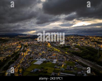 Vista aerea delle nuvole di tempesta drammatiche sopra le luci della città distesa all'alba Foto Stock