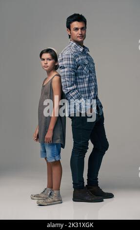 Bei hippsters. Studio shot di un padre e un figlio alla moda di nuovo alla schiena su uno sfondo grigio. Foto Stock