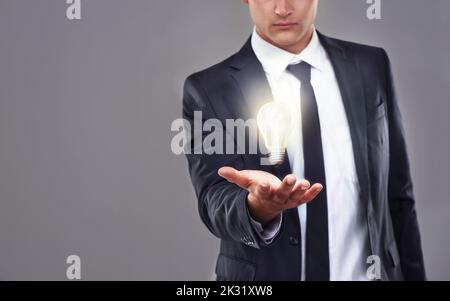 Illuminare la strada verso pratiche aziendali sostenibili. Un uomo d'affari che tiene una lampadina luminosa. Foto Stock