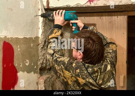 Foratura di un foro in una parete di cemento con un punzone Foto Stock