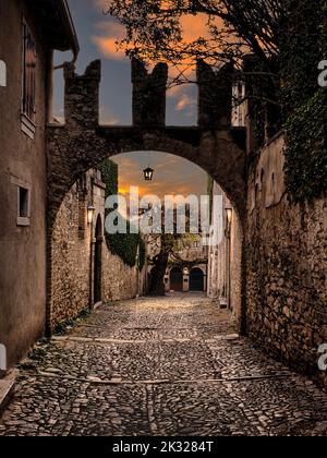 San Vigilio al tramonto, Lago di Garda, Italia. L'antica strada asfaltata che conduce a Punta San Vigilio sul lago. Foto Stock