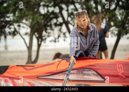 Una giovane concorrente femminile allestì le sue attrezzature per competere con la gara nazionale neozelandese di aliscafi per il windsurf al Waterbourne Watersports Festival Foto Stock