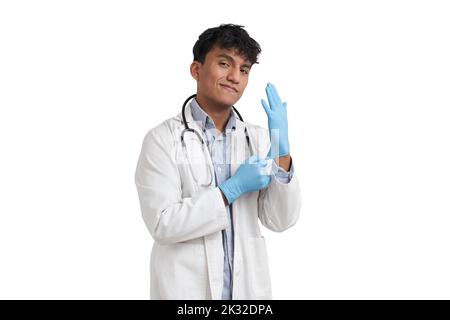 Giovane medico peruviano maschio indossando guanti blu, isolato. Foto Stock