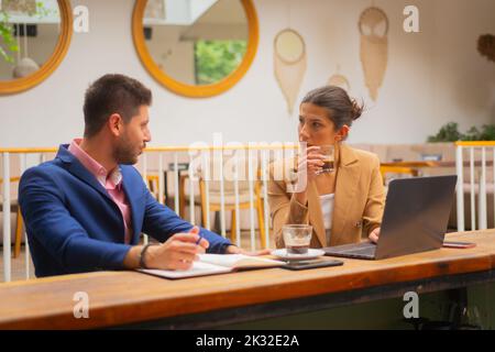 Due bei colleghi stanno facendo una seria conversazione di lavoro dopo il lavoro, sulla terrazza di un caffè Foto Stock