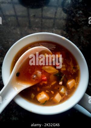 Zuppa di verdure calda e acida preparata in casa in un recipiente bianco con un cucchiaio. Uttarakhand India. Foto Stock