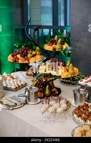 Matrimonio. Candy bar. Sul tavolo del buffet ci sono bicchieri con bevande, frutta e dolci diversi. Foto Stock