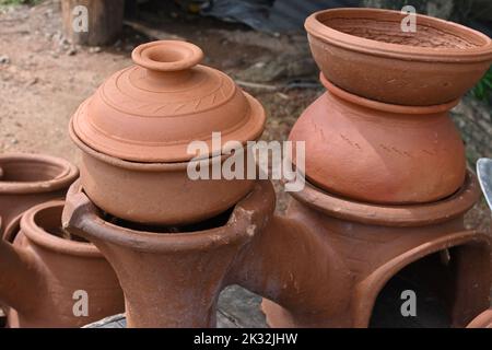 Una pentola di creta di cottura (pentola) con coperchio coprente sopra con un altro grande pentola di creta di cottura su una stufa di creta doppia per vendere Foto Stock