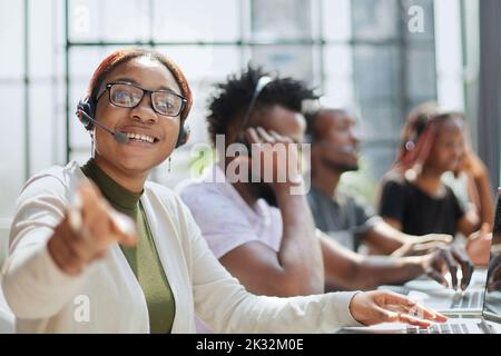 Sorridente bella donna afroamericana che lavora in call center con team diversi Foto Stock