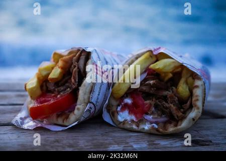 un paio di gustosi gyros di maiale greco avvolti su un tavolo di legno. Foto Stock