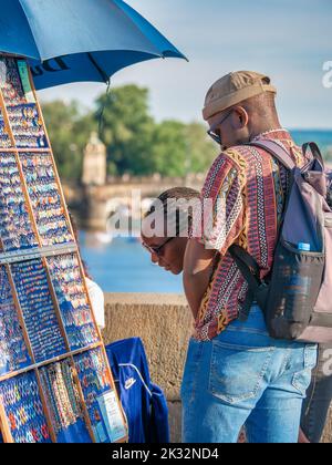 Praga, Repubblica Ceca - Giugno 2022: Turisti afro-americani sul famoso Ponte Carlo di Praga in cerca di souvenir Foto Stock