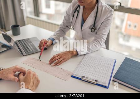 Foto di una dottoressa afro-americana, che mostra la frequenza cardiaca dei pazienti con una penna alla sua collega. Foto Stock