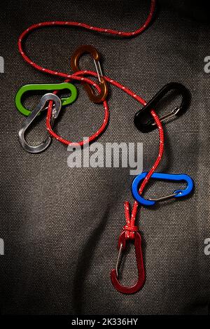 accessori per moschettone colorati su una piccola corda rossa. Questo attrezzo non è adatto per arrampicarsi Foto Stock