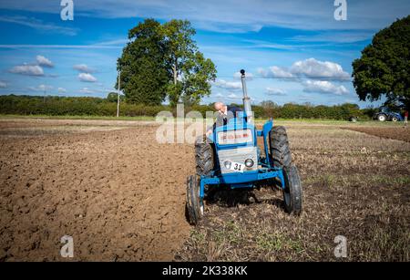 Un concorrente di una tradizionale partita di aratura agricola siede sul suo trattore blu vintage mentre aratri la sua zona alla Oakhurst Farm, vicino a Billingshurst, 24 settembre 2022. Le partite di aratura sono popolari nelle comunità rurali e agricole britanniche e si svolgono ogni autunno dopo il completamento della raccolta. Credit: Andy Soloman/Alamy Live News Foto Stock