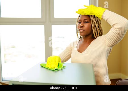 Bella giovane donna latino-americana in guanti di protezione pulizia a casa Foto Stock