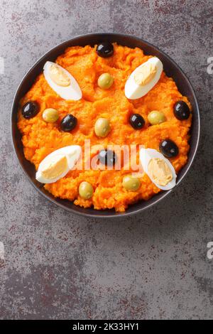 Omek Houria è un'insalata tunisina, fatta con carote, harissa, aglio, aceto, olio d'oliva servito con uova e olive primo piano nel piatto sul tavolo. Foto Stock