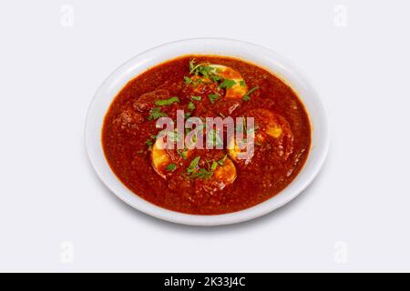 Primo piano di masala d'uovo o curry d'uovo preparato con cipolla, aglio e una miscela di spezie indiane in un recipiente. Foto Stock