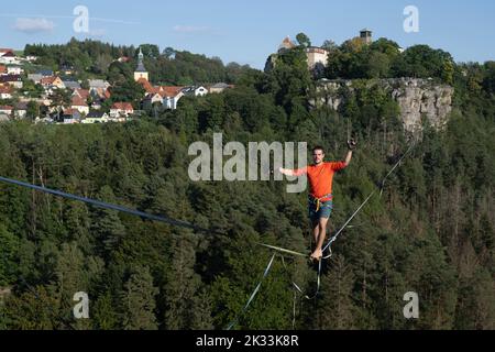 Hohenstein, Germania. 24th Set, 2022. Il corridore slackline Gregor Lawrenz corre alla Highline - e festa di famiglia su una corda lunga 360 metri tra il castello Hohnstein e l'Hockstein in 110 metri di altezza sul Polenztal. Credit: Sebastian Kahnert/dpa/Alamy Live News Foto Stock