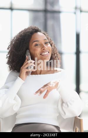 Ritratto di una giovane donna afroamericana attraente utilizzando uno smartphone Foto Stock