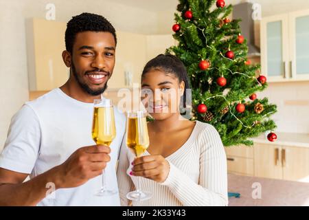 felice coppia che tiene un bicchiere di champagne e festeggia il nuovo anno a casa Foto Stock
