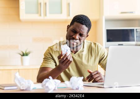 L'uomo ha schiacciato la carta mentre lavora e non ha idea di lavoro remoto in cucina Foto Stock