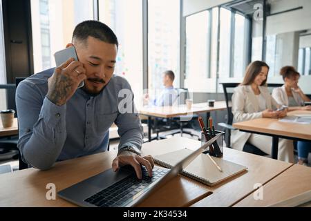 Dipendente aziendale concentrato che digita sul proprio notebook Foto Stock