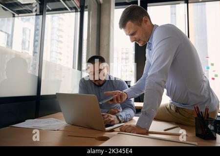 Dipendenti aziendali che inviano file da un dispositivo mobile a un computer portatile Foto Stock