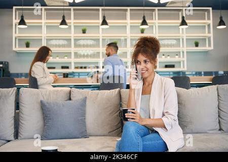 Donna che tiene una conversazione telefonica alla pausa caffè Foto Stock