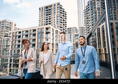 Gruppo di lavoratori aziendali che camminano sul balcone dell'ufficio Foto Stock