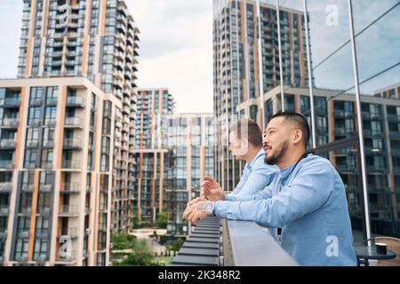 Due premurosi dipendenti dell'azienda si alzano sul balcone dell'ufficio Foto Stock