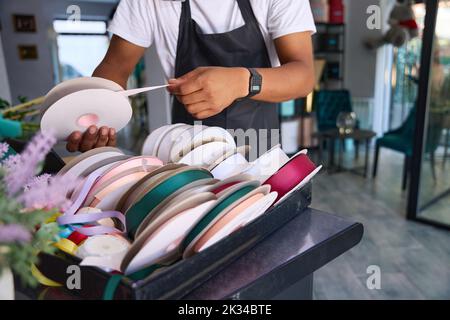 L'uomo multirazziale in un grembiule sceglie un nastro Foto Stock