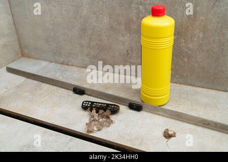 Detergente liquido in un flacone giallo per la pulizia degli scarichi delle fognature. Pulire lo scarico della doccia con detergenti liquidi. Foto Stock