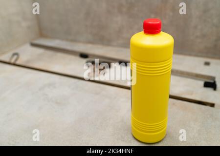 Detergente liquido in un flacone giallo per la pulizia degli scarichi delle fognature. Pulire lo scarico della doccia con detergenti liquidi. Foto Stock