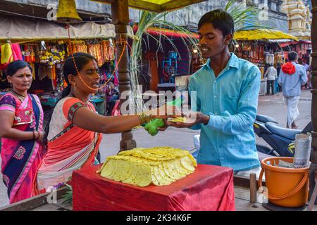 Tuljapur, India- Dicembre 19th 2019; Foto di scorta di un uomo di 25 a 30 anni che vende ananas fresco succoso affettato a una cliente femminile nel mercato area.SL Foto Stock