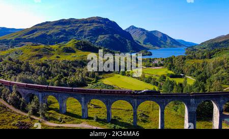 Regno Unito, Scozia, Viadotto di Glenfinnan con treno a vapore che passa sopra. Viadotto di Harry Potter e carrozze di stile espresse di hogwarts. Foto Stock